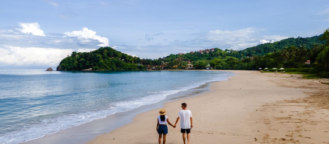 Aerial view from a drone of a man and woman walking at a tropical beach in Koh Lanta Thailand. couple walking on a white beach